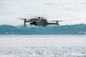drone hovers above frozen expanse, raw beauty snowy terrain with distant mountains. its camera...