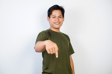 A smiling young Asian man wearing a green shirt points down	
