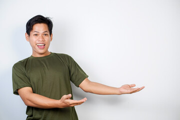 Portrait of a cheerful man in green pointing amiably to blank space, ideal for presentations,...