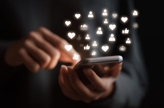 A person typing on their phone with icons of thumbs up, likes, and hearts floating above the screen in an animated style., 
