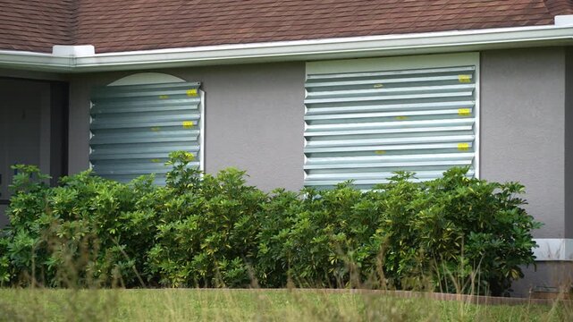 Storm shutters mounted on Florida house windows for hurricane protection. Preparing for natural disaster