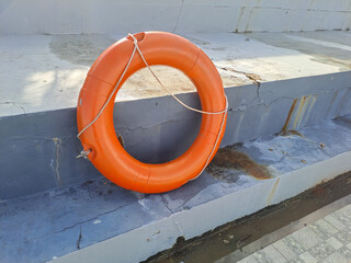 A Bright Orange Lifebuoy Hanging on a Stone Wall for Safety	
