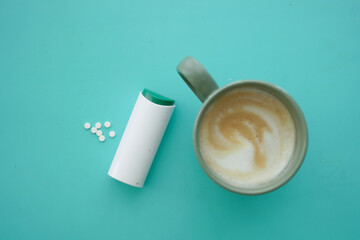 Artificial sweeteners and a cup of coffee on color background ,