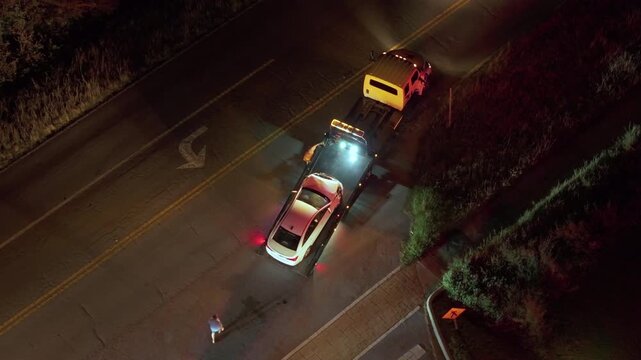 Tow truck hauling damaged car in traffic accident from crash site on American road.