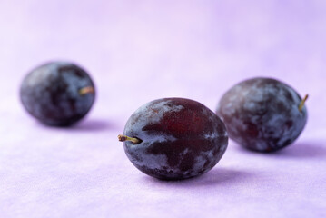 Fresh blue plum fruit on purple background