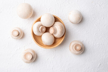 Top view of fresh white Champignon mushroom (botton mushroom) in wooden bowl on white background, Edible mushroom, Food ingredients