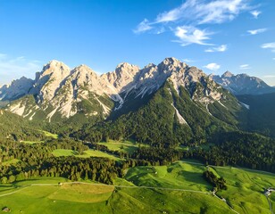 Panoramic view of majestic mountain range under a clear blue sky, lush green valley below