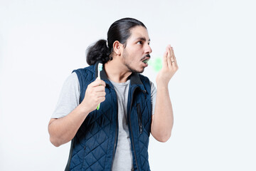 Man with bad breath holding a toothbrush isolated. Young male with halitosis on white background