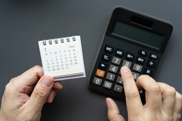 Hand Holding 2025 JANUARY Calendar and Using Calculator, 2025 JAN Financial Planning Concept....