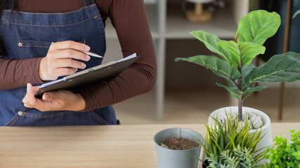 Floral Business Owner Taking Notes in a Green Workspace