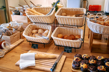 A delightful spread of freshly baked goods including various types of bread, pastries, and desserts arranged neatly on a wooden table in a welcoming setting.