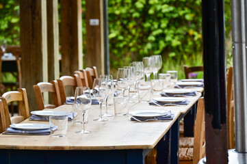 Large outdoor dining table formal decorated and set with tablecloth, napkins and wine glasses