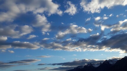 Obraz premium Vibrant sky with dramatic clouds over snow-capped mountains at sunset