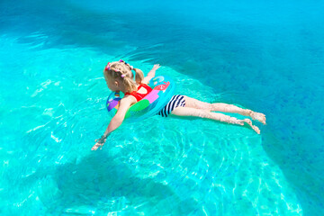 A joyful child is happily enjoying the beautiful summer sun, swimming in a bright, colorful pool depicting an airplane