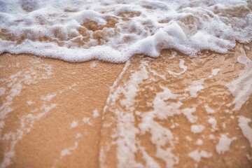 Golden sand meets gentle waves at the shoreline during a calm morning