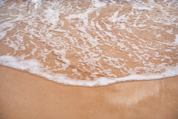 Gentle waves lapping on the sandy beach at sunset creating a tranquil coastal atmosphere