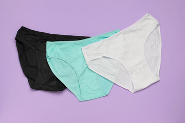 Colorful Trio of Underwear on Purple Background: Black, Mint, and White Cotton Panties
