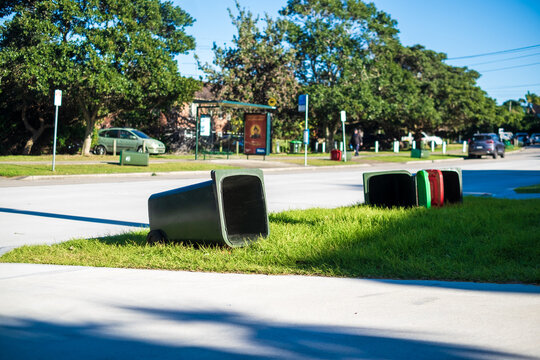 bins scattered on the sidewalk on a windy day