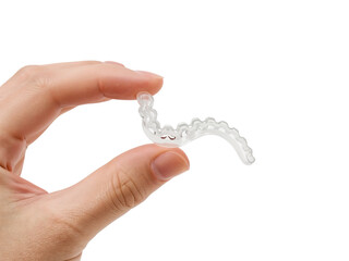 Hand delicately holding a transparent dental aligner against an isolated background showcasing