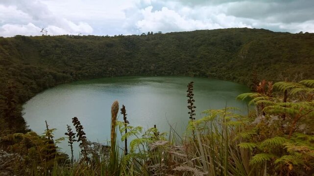 Panoramic view panning to the right of the Guatavita lagoon, where the legend of El Dorado began, a tourist site in Colombia on a cloudy day.