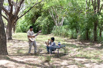 Fototapeta premium Two men are enjoying time outdoors. One is focused on playing an acoustic guitar, while the other engaged in a shared activity.a moment of pure friendship, shared joy.