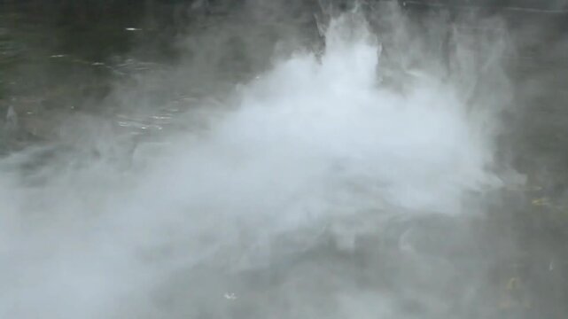 waterfall in the fog, White smoke bursts from the pipe in the middle of the pool, forming a white layer on the water, and then disappears in the wind