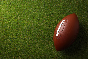 A classic football rests on lush green grass under clear skies