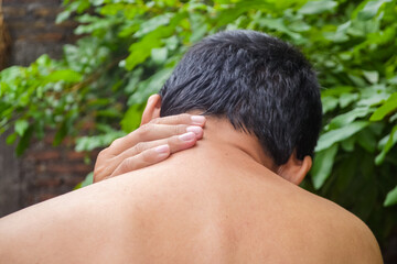 Back of a man. Close-up of a man touching his painful neck, indicating neck pain, muscle strain or...