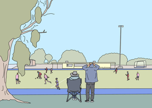 Two adults watching children play winter hockey game from sidelines
