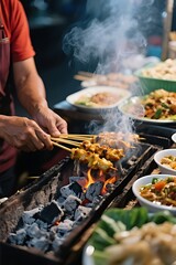 Fototapeta premium a street vendor grilling sate over charcoal with smoke rising