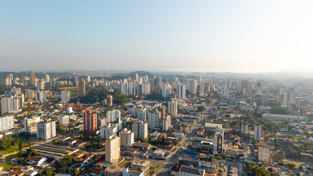 Aerial cityscape of Joinville, Santa Catarina, Brazil, featuring tall buildings and urban sprawl under clear skies.