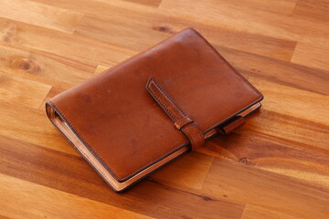 茶色の革のシステム手帳でデスクワークをしているイメージ
