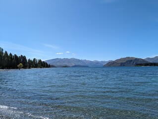Naklejka premium clear blue lake with mountains and trees