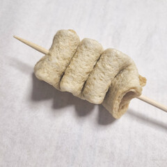 A series of images demonstrating the process of preparing fish cake skewers. The first image shows...