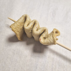 A series of images demonstrating the process of preparing fish cake skewers. The first image shows...