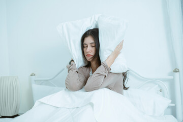 A young woman who wakes up in the middle of the night in bed with symptoms of anxiety, stress,...