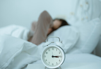 A young woman who wakes up in the middle of the night in bed with symptoms of anxiety, stress,...