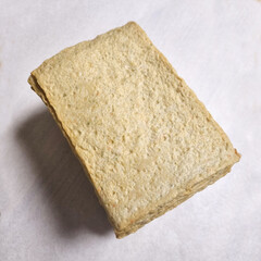  A series of images demonstrating the process of preparing square fish cake pieces. The first few images show a person's hand picking up and folding the thin slices of fish cake. Subsequent images sho