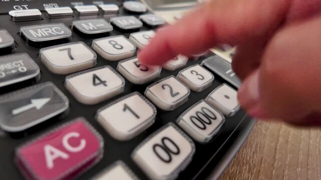 Slow-motion close-up of hands using a calculator to count numbers