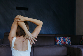 close-up view of a back of a woman sitting in Cow Face yoga pose doing exercise at home