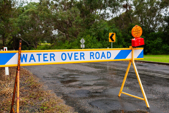 Water over road sign blocking off road during flooding on rainy day