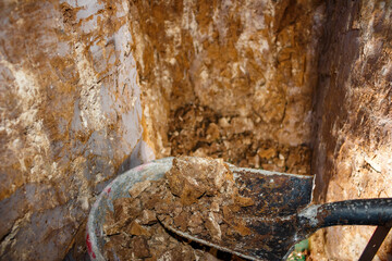 Putting soil into a bucket while manually digging a tunnel with a shovel