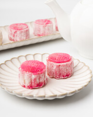 Homemade Chinese snow skin mooncakes. Snowy Moon cakes with Rose Bud Tea and White Teapot on White Background. Mid-Autumn Festival, traditional Asian desserts, and seasonal celebrations in Asian count
