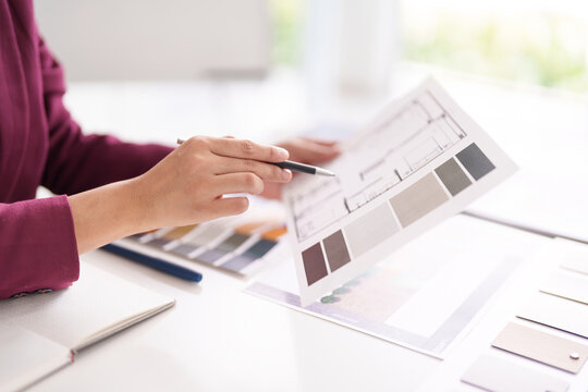 Architectural designer hands review blueprint floor plan selecting color swatches for home interior design project professional workspace planning development