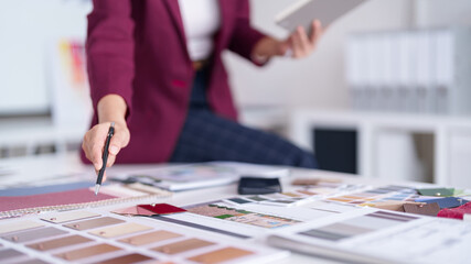 `Adult Asian woman professional architect interior designer selects color material swatches for home architectural project planning office design studio`