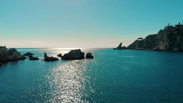 Aerial view of the sparkling blue ocean with rocky cliffs, reflecting coastal light. A serene and peaceful scene captured from Praia do Camilo, Portugal, offering stunning natural beauty