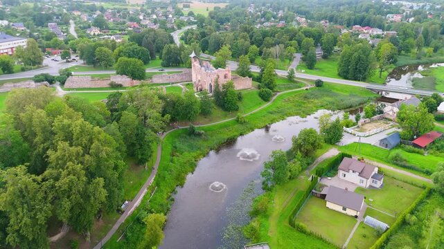Aerial View of Dobele Castle Ruins, Flowing Berze River and Illuminated Fountains at Sunset Serene Latvian Summer Evening from Above, Scenic Aerial of Latvian Historical Landscape in Golden Hour