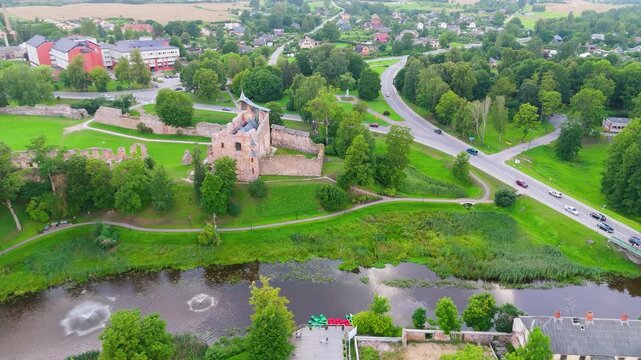 Aerial View of Dobele Castle Ruins, Flowing Berze River and Illuminated Fountains at Sunset Serene Latvian Summer Evening from Above, Scenic Aerial of Latvian Historical Landscape in Golden Hour