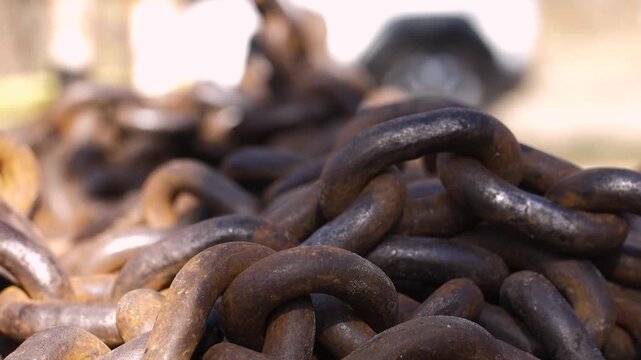Slow motion footage of heavy rusty chains dropping and hitting surface, showing impact and chain movement