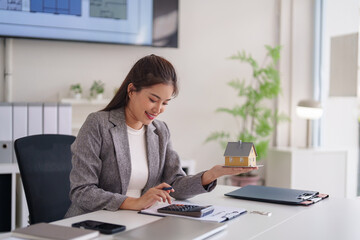 Asian Real Estate Agent Adult Woman Holds House Model Calculates Home Costs Property Investment Finance Planning Modern Office Environment